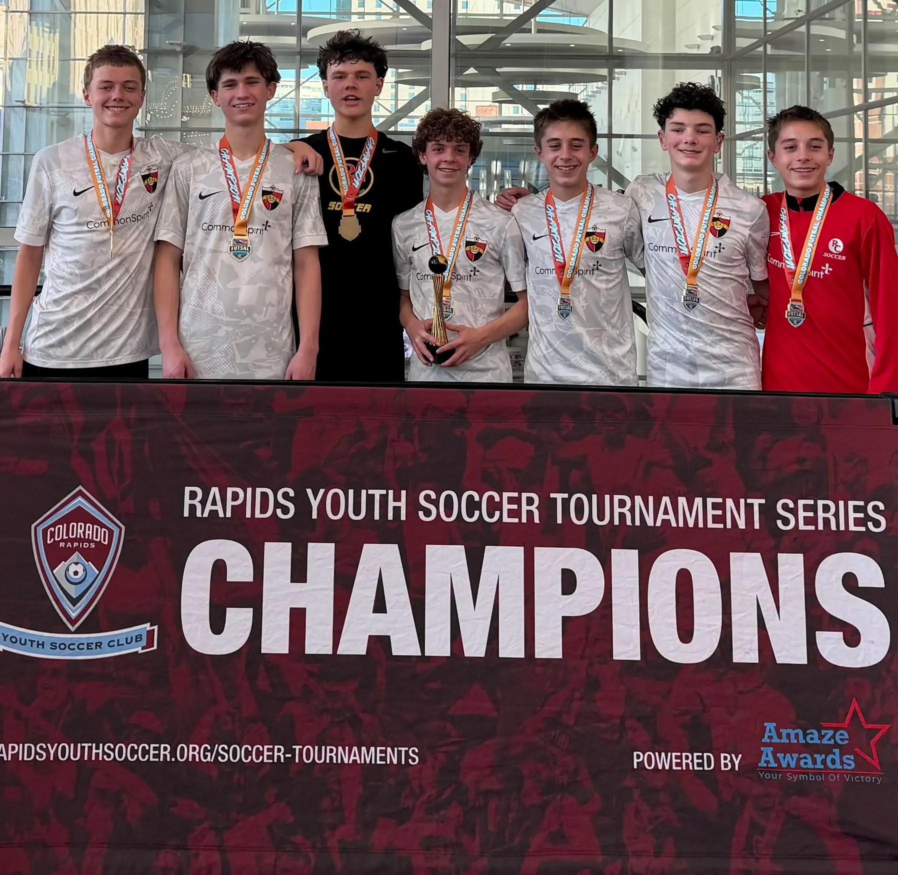 Real Colorado Academy team with gold medals under Colorado Rapids Youth Soccer Tournament Series Champions banner